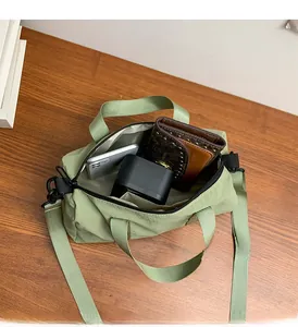 Spacious interior of light green nylon crossbody bag showing storage for phone and wallet