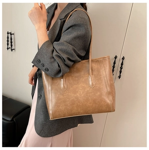 Model wearing a large vintage brown tote bag made of oily leather material for work