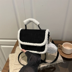 Plush black saddle bag with fuzzy faux fur trim and matching round coin purse on a table