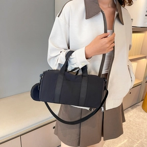 Detailed view of a black nylon cylinder bag with top handles and a detachable shoulder strap