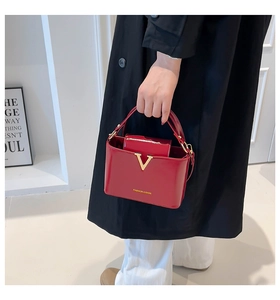 Detail of red glossy leather bucket bag with gold V buckle and Fashion & Bags lettering