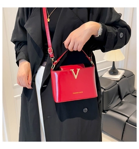 Detail of red patent leather bucket bag with gold V logo and slim shoulder strap