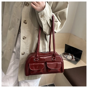 Dettaglio borsa a spalla in pelle verniciata rosso scuro con doppie tasche a patta