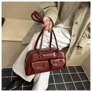 Dettaglio della borsa in pelle verniciata rosso vino con tasche frontali e finitura lucida