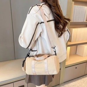 Detail of beige nylon cylinder crossbody bag with a round coin purse on shoulder strap