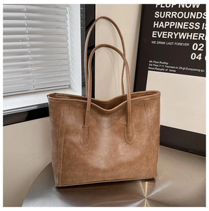 Close-up of brown vintage tote bag with wrinkled leather texture on a metal table