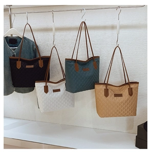 Detailed view of quilted tote bags in black, white, teal and khaki colors on hooks