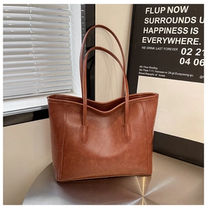 Minimalist vintage brown tote bag made of matte faux leather on a metal display stand
