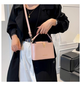 Pink bucket bag with gold V-metal decor shown on model in a modern indoor setting