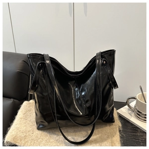 Close-up of glossy black leather tote bag featuring a soft texture and dual shoulder straps