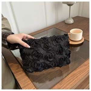 Detailed view of handmade black fabric rose petals on an elegant evening clutch bag