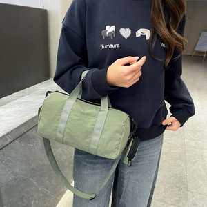 Close-up of light green nylon cylinder bag featuring a detachable mini round coin purse