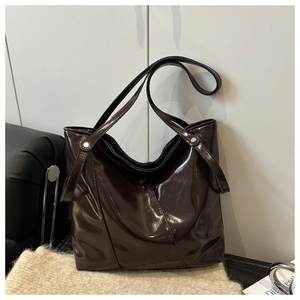 Detail of dark chocolate glossy patent leather tote with silver rivet hardware