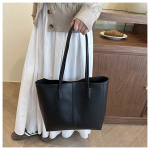 Détail du sac cabas en similicuir noir montrant les coutures et la bandoulière longue