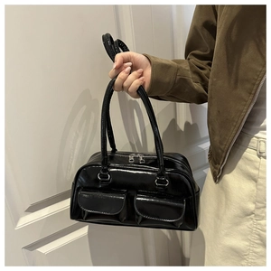 Dettaglio della borsa nera in pelle verniciata lucida con tasche a patta e cerniera