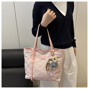 Dettaglio della borsa tote rosa a pieghe con ricami floreali e ciondolo a forma di orso