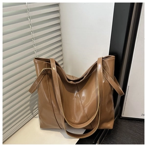 Detailed view of caramel brown faux leather tote bag with reinforced stitching and dual handles