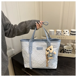 Dettaglio della borsa tote azzurra con ricamo floreale e ciondolo a forma di orso