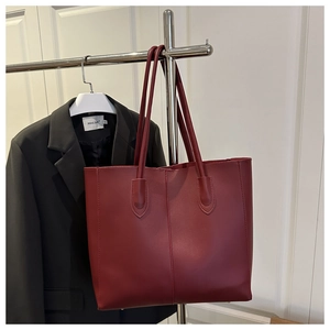 Gros plan du sac cabas bordeaux avec couture centrale et longues anses sur un cintre