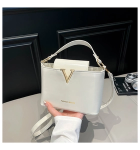 Detailed close-up of white leather bucket bag with gold V-metal logo and top handle