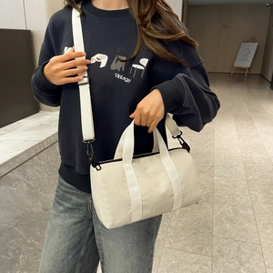 Crossbody view of lightweight nylon cylinder boston bag with adjustable strap and side pocket