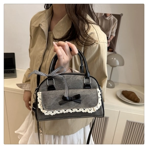 Détail du sac à bandoulière en denim anthracite avec bordure en dentelle et noeud