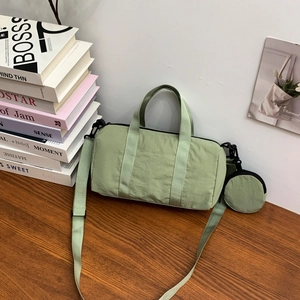 Detail of light green nylon Boston bag with matching round coin purse on wooden desk