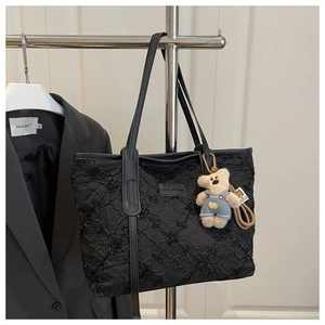 Dettaglio della borsa tote nera con texture plissettata e decorazione di paillettes lucide