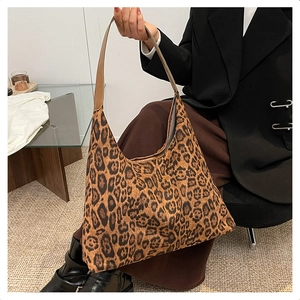 Close-up of leopard print velvet tote bag with brown leather strap in home setting