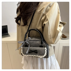 Gros plan du sac bandoulière en denim gris avec dentelle et nœuds décoratifs sur un bureau