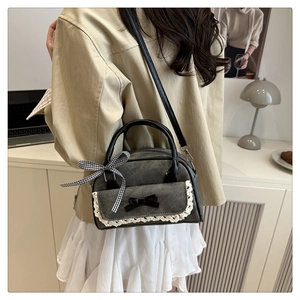 Détail du sac gris foncé avec dentelle noire et ruban à carreaux sur la poignée