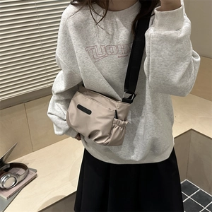 Minimalist beige nylon crossbody tote bag for women shown in a casual indoor setting