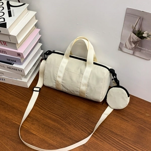 Macro detail of beige nylon barrel bag featuring black hardware and round coin purse