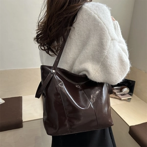 Minimalist dark brown patent leather tote bag for women showing sleek shoulder carry style