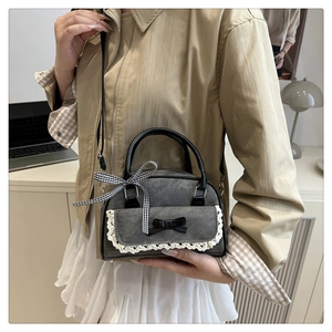 Détail du sac en toile grise avec bordure en dentelle blanche et nœuds en cuir noir