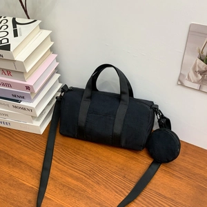Detail of black nylon cylinder bag with mini purse on a wooden table setup