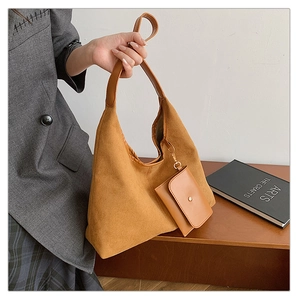 Detail of suede hobo tote with mini pouch attachment on a wooden bench setting