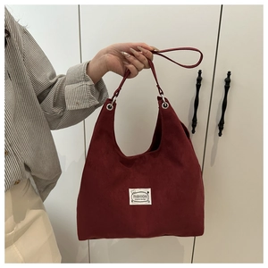 Detail of burgundy suede Hobo bag with Fashion cloth label and silver metal rings