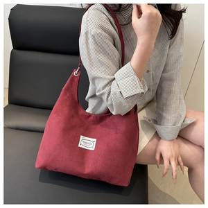 Close-up of minimalist burgundy underarm bag with fashion label on shoulder of model