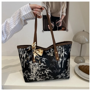 Detail of printed fabric tote bag with bamboo patterns and brown leather handles