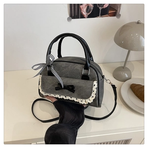 Vue détaillée du sac bandoulière en denim gris avec nœuds noirs et finitions dentelle