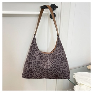 Detail of grey leopard print hobo bag hanging on door showing soft fabric and brown strap