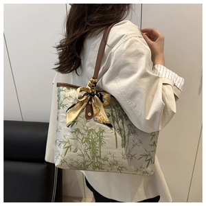 Detail of canvas tote bag with bamboo print, leather straps and a decorative silk scarf