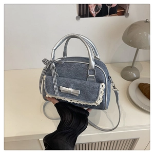 Détail du sac Boston en denim avec dentelle, nœud argenté et ruban à carreaux décoratif