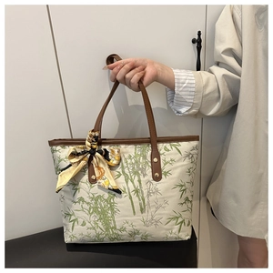 Detail of canvas tote bag with bamboo print, leather handles and decorative silk scarf