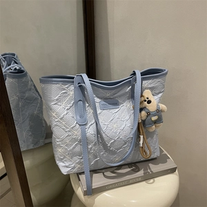 Borsa tote celeste ricamata a fiori con trama a pieghe e ciondolo a forma di orsetto
