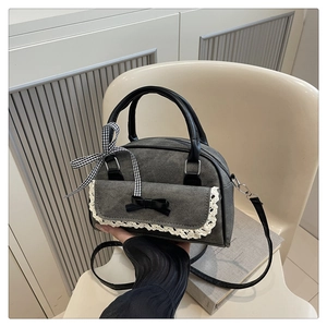 Détail du sac bandoulière en denim gris avec bordure en dentelle et nœud noir
