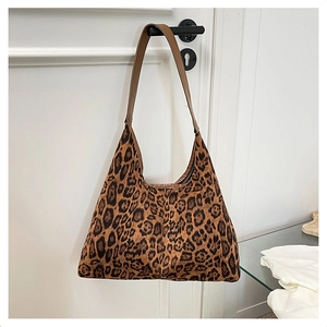 Detailed view of leopard print hobo bag with brown leather strap on a door handle