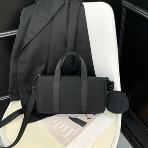 Minimalist black nylon cylinder bag with matching coin purse and adjustable strap