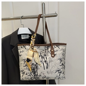 Detail of a white tote bag with bamboo ink print and a silk scarf on the handle